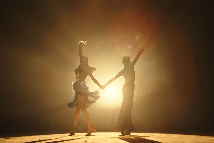 Two Dancers Holding Hands Under A Spotlight
