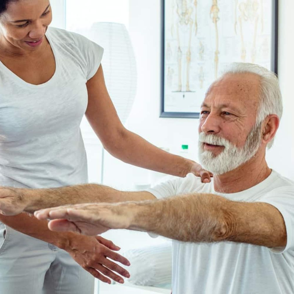 A Physical Therapist Helps An Older Man Through Exercises.