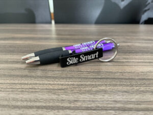 A pen and a cellphone holder branded with Site Smart.